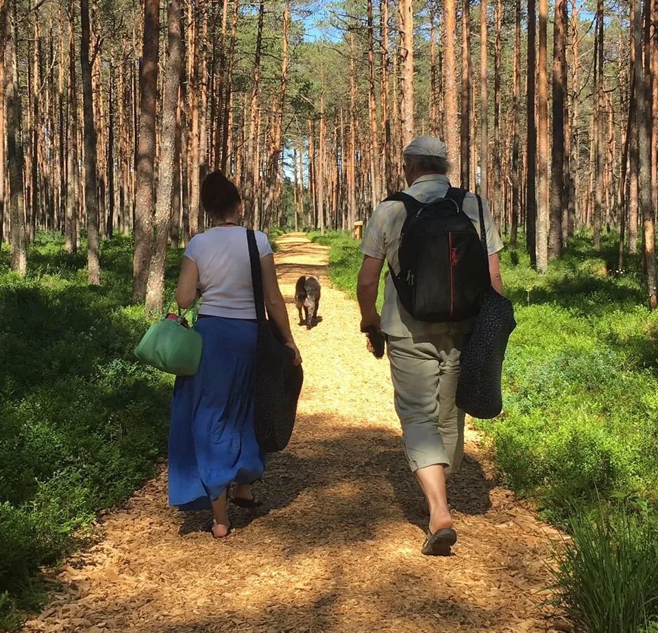 Kaks inimest ja koer päikeselisel metsateel